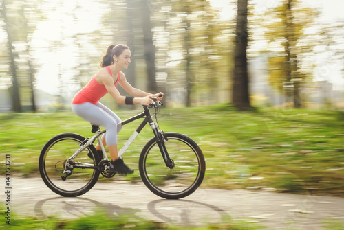 Carefree woman riding bicycle in park having fun on summer afternoon