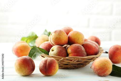 Sweet peach fruit in basket on white wooden table
