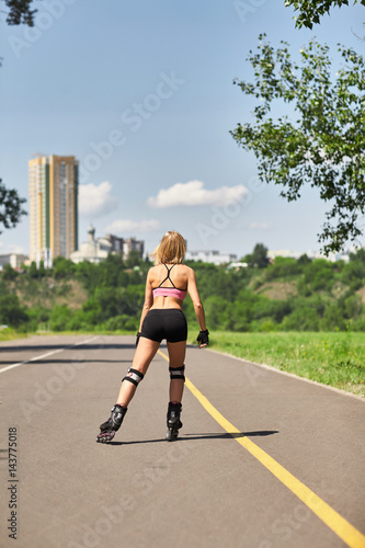 Fit  sporty and athletic young woman. Beautiful girl rollerblading on skates in a sportswear.