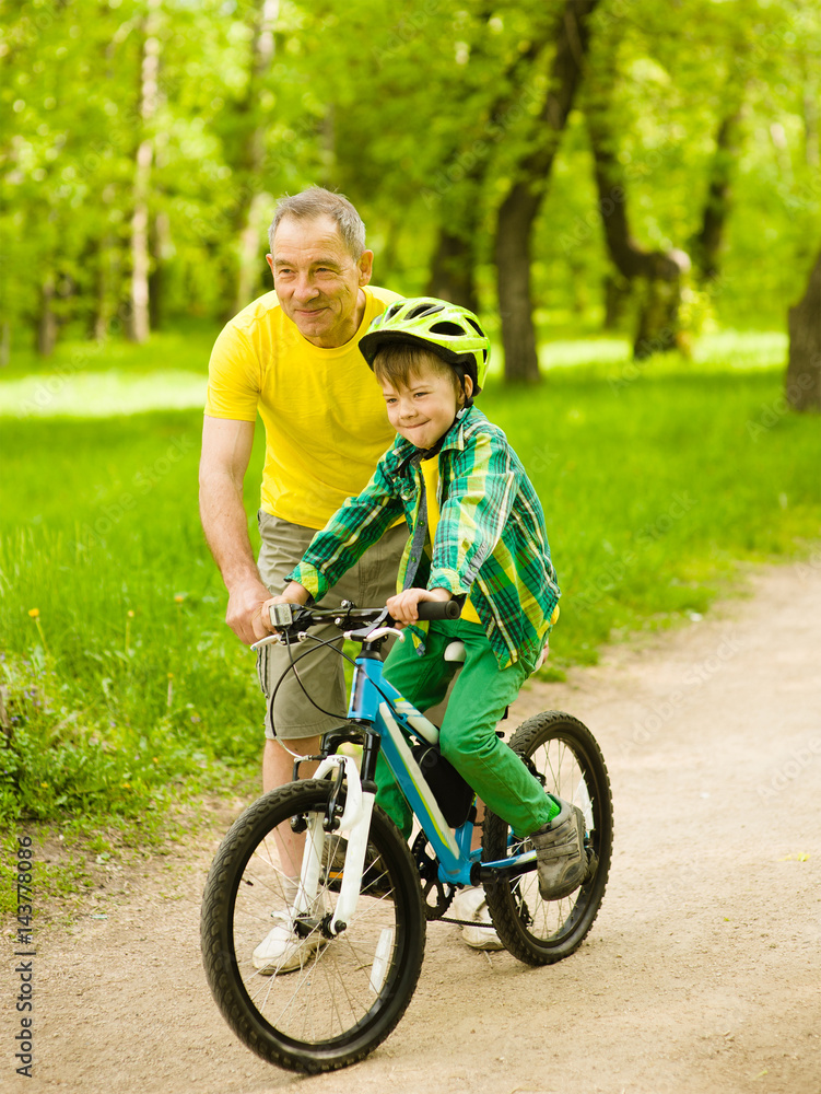 Grandfather teaches his grandson to ride a bike Grandfather teaches his grandson to ride a bike