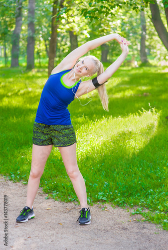 beautiful young woman stretching the muscles of her arms and back before jogging © Ermolaev Alexandr