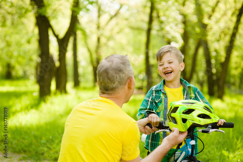 Grandfather gives his grandson a bicycle helmet
