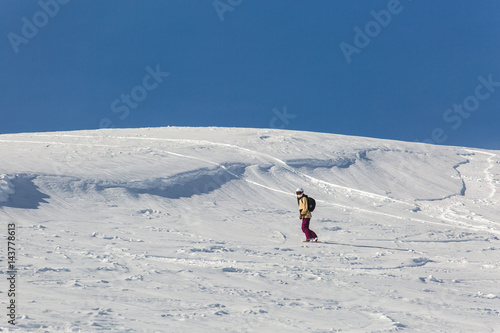 women snowboarder snowboarding on fresh white snow with ski slope on Sunny winter day