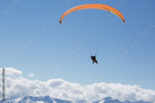 Parachute sky-diver flying in clouds above mountains. Travel adventure concept. space for text