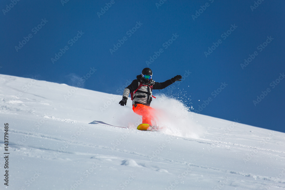  snowboarder snowboarding on fresh white snow with ski slope on Sunny winter day