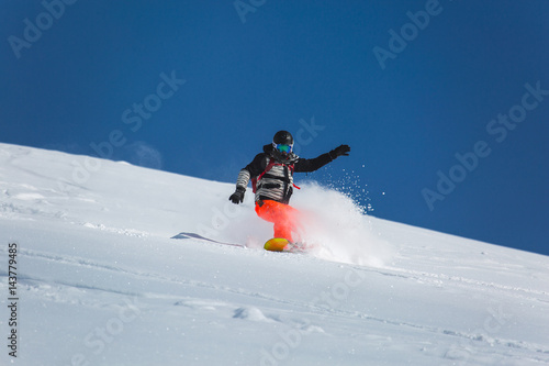  snowboarder snowboarding on fresh white snow with ski slope on Sunny winter day