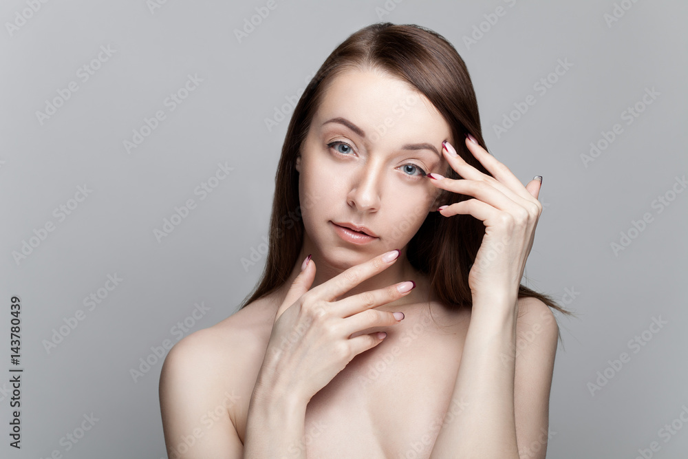 Isolated on gray background studio portrait of young brunette with manicure on nails