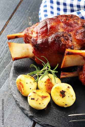 Photography Smoked ham hock with herbs and spices on wooden plate.