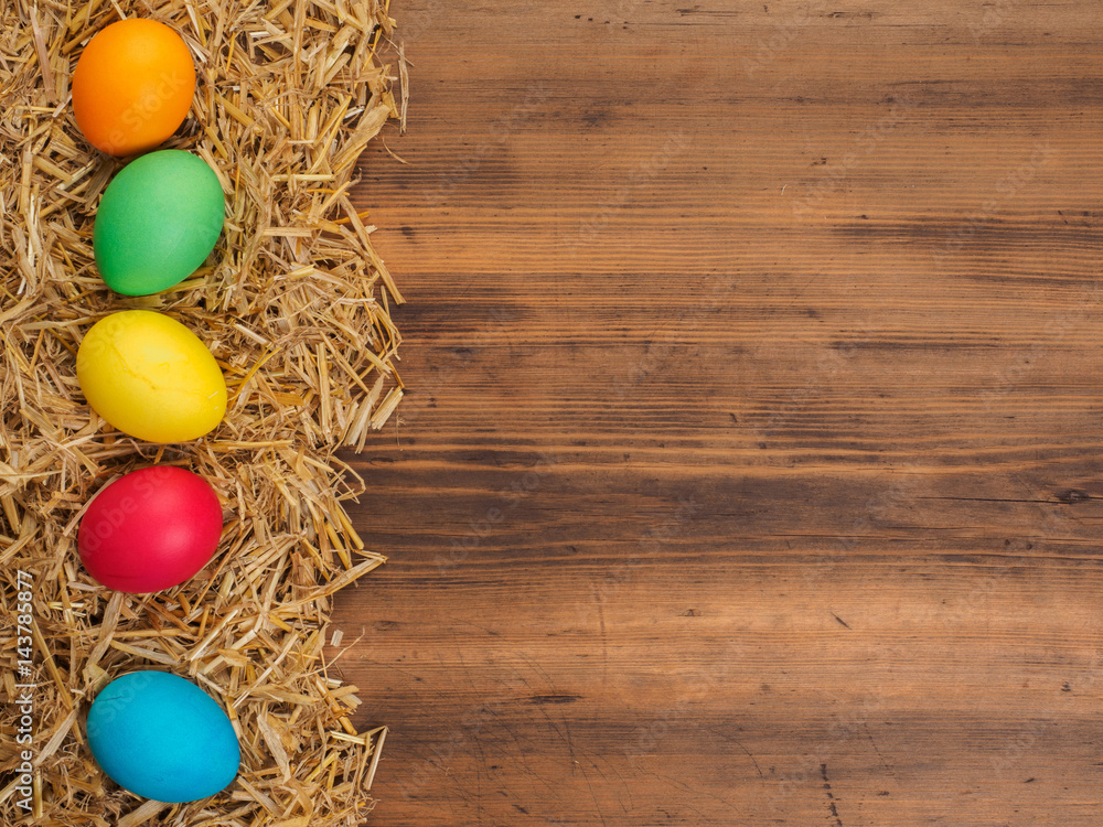 Rural eco background with colored chicken eggs and straw on the background of old wooden planks. The view from the top. Creative background for Easter cards, menu or advertising Rural eco background with colored chicken eggs and straw on the background of old wooden planks. The view from the top. Creative background for Easter cards, menu or advertising