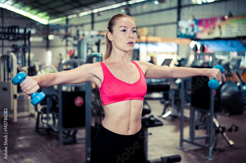 Pretty fitness girl with dumbbells. Attractive woman in gym. © zulman