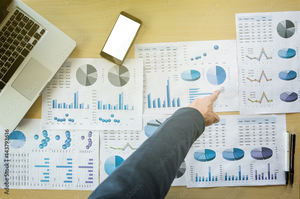 Businessman pointing documents at office working table with smart phone and computer, Top view. Businessman pointing documents at office working table with smart phone and computer, Top view.