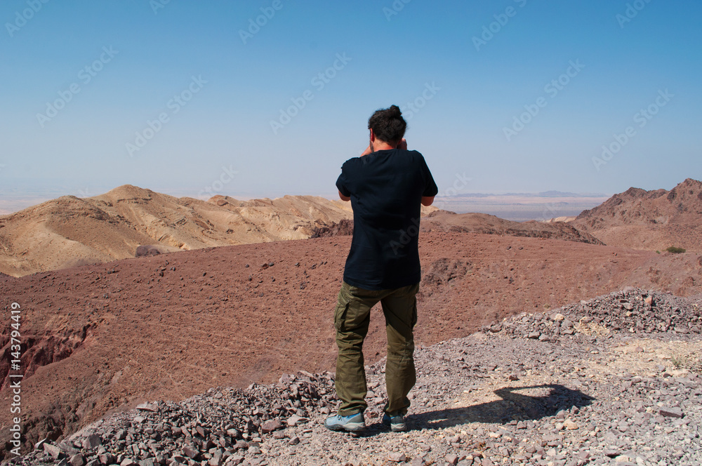 Medio Oriente, 10/03/2013: un uomo di spalle fotografa il paesaggio deserto sulla strada che collega la Riserva Biosfera di Dana, la più grande riserva naturale della Giordania, a Petra