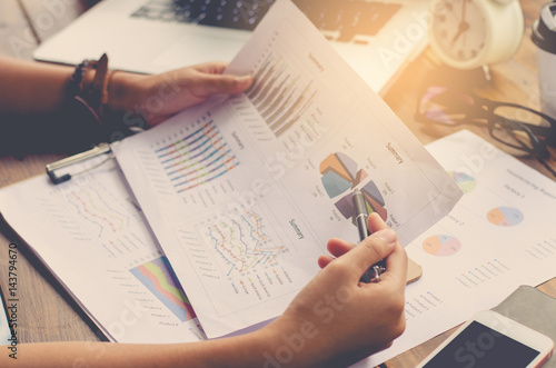 Businessman holding paperwork on the table and analyzing investment chart working in office. Business work concept.