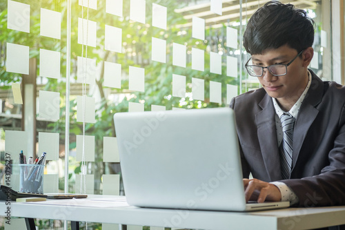 Confident young businessman working on laptop at creative office photo