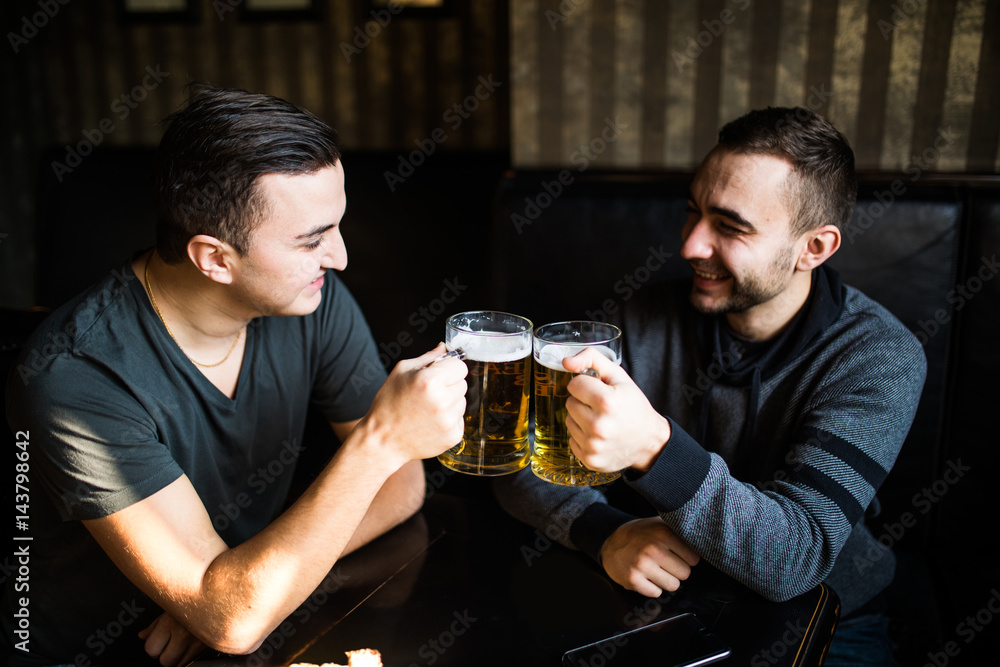 two young man sitting in pub, eating and drinking beer at pub two young man sitting in pub, eating and drinking beer at pub