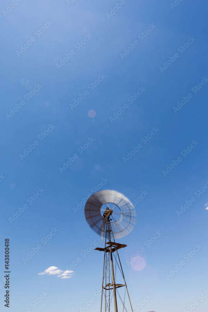 Close up wide angle image of a windmill / windpomp with spinning blades, pumping water in the Tankwa Karoo in South Africa on a hot summersday Close up wide angle image of a windmill / windpomp with spinning blades, pumping water in the Tankwa Karoo in South Africa on a hot summersday