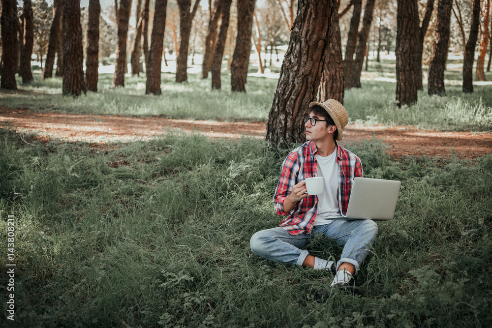 Boy having coffee in nature with a laptop Boy having coffee in nature with a laptop