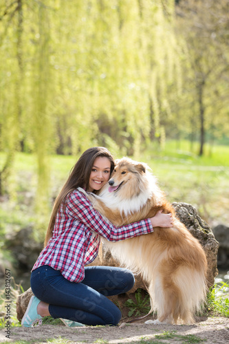 young beautiful woman with long hair walking with collie dog. Outdoors in the park.