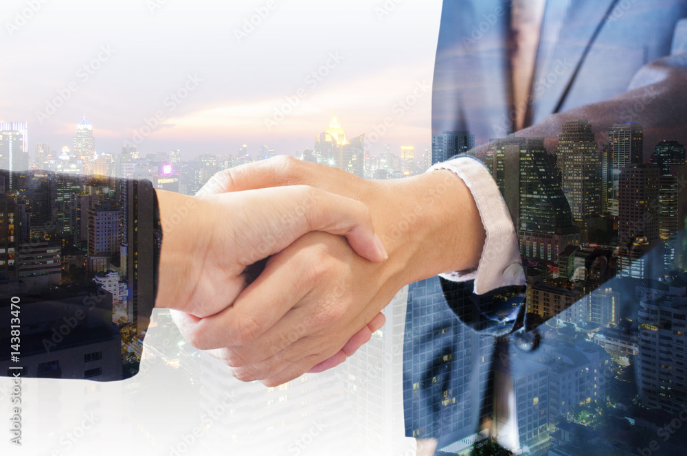 Double exposure of businessman and businesswoman handshake agree deal with city of business in blue tone background