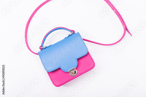 Small isolated leather woman handbag in pink and blue colors lying on a white background