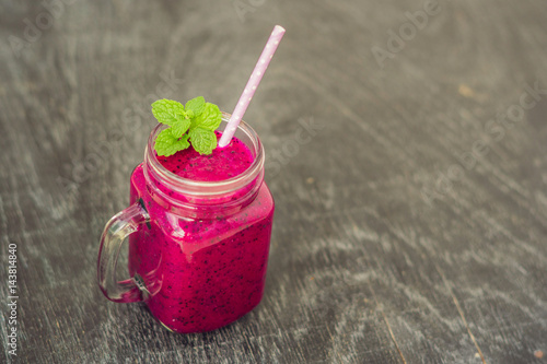 Smoothies of a red organic dragon fruit on an old wooden background photo