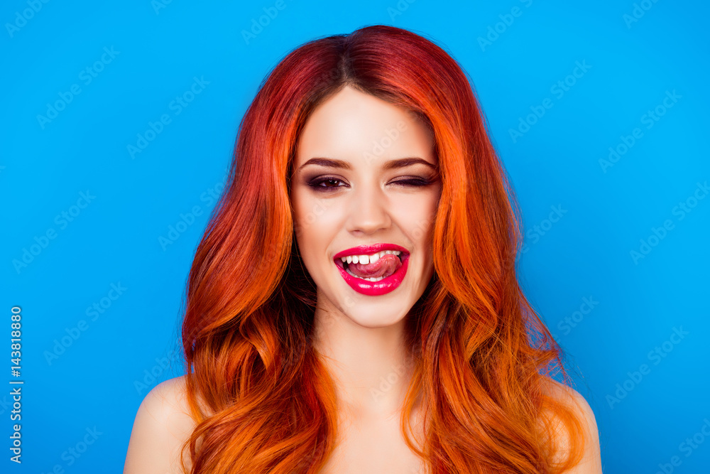 Fototapeta premium close up portrait of funny attractive pretty girl with long ginger fair hair put out her tongue while standing on blue background