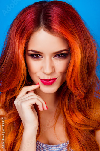 Close-up portrait of funny sly attractive girl with long ginger with dye ombre fair hair touch her face with fingers and smiling