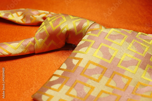 Bright pink with yellow necktie on orange background, fashion accessory close up
