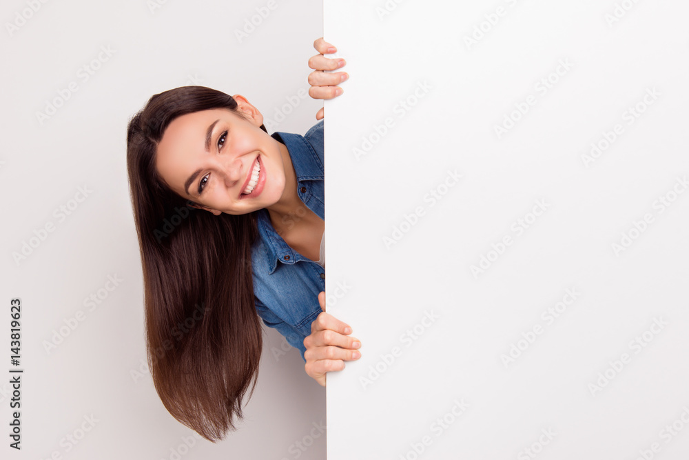 Young smiling long-haired girl standing and appear near big poster, place for copy space Young smiling long-haired girl standing and appear near big poster, place for copy space