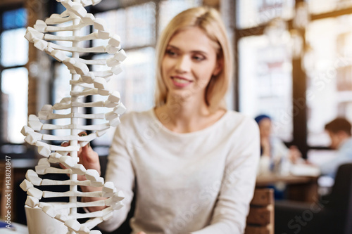 Smiling beautiful young student studying DNA model