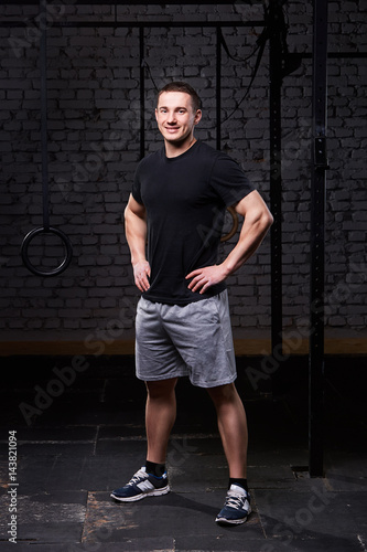 Photo of a young crossfit sportsman in sportwear while standing against brick wall. photo