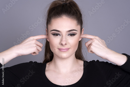Картината върху платно Young attractive woman with fingers in her ears