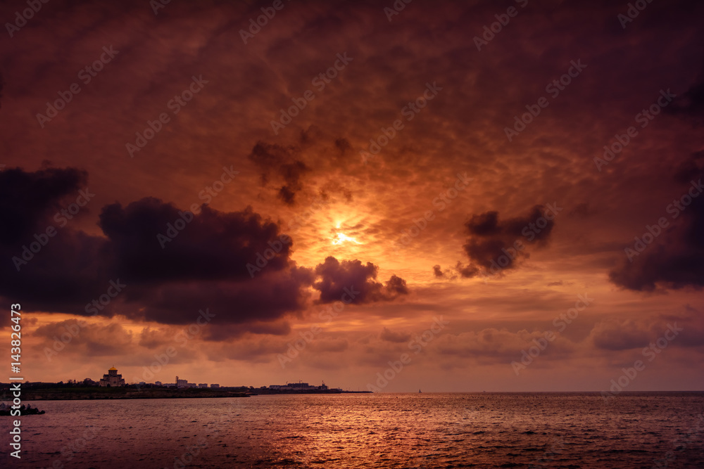 Naklejka premium Gloomy sunset with dark clouds above the calm sea