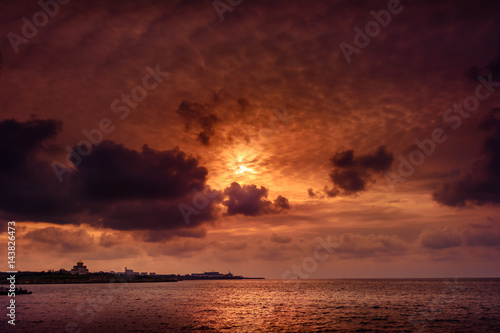 Gloomy sunset with dark clouds above the calm sea