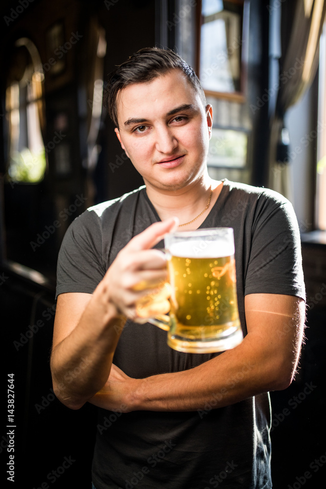 man in a pub or bar holding mug the beer high in the air for cheers
