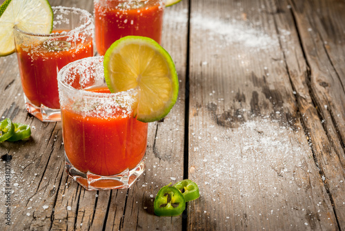 Mexican traditional alcohol drink. Sangrita, with tequila, tomato juice, hot spices, chili and lime.Analogous bloody mary. On rustic wooden table, copy space photo