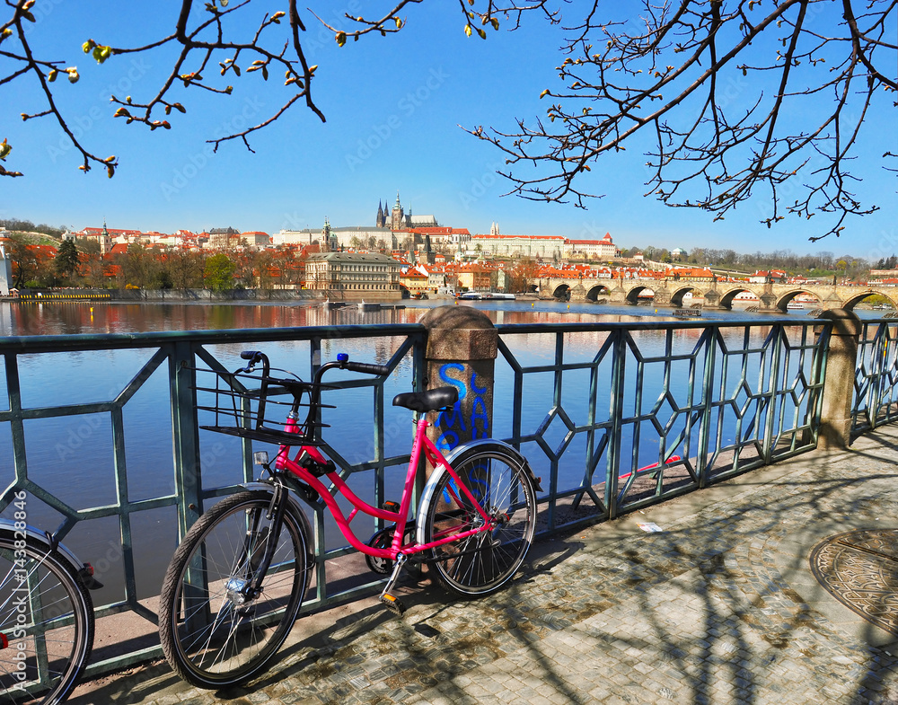 Fototapeta premium Prague Castle with famous Charles Bridgea and with pink bike in the foreground in Czech Republic