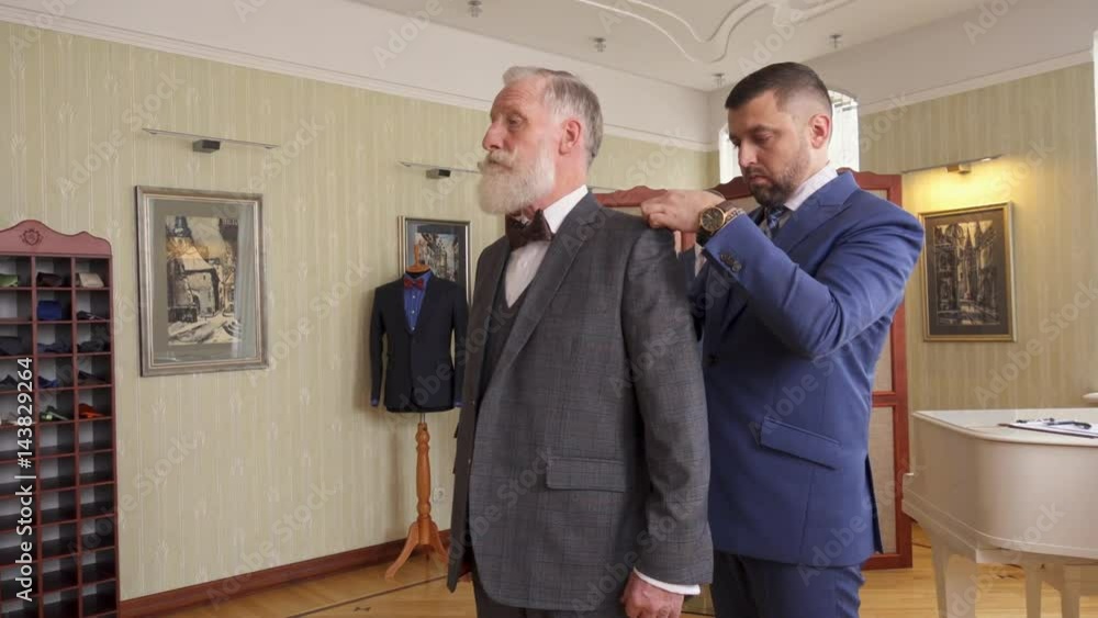 Tailor adjusting sutom made suit on a senior client Tailor adjusting sutom made suit on a senior client