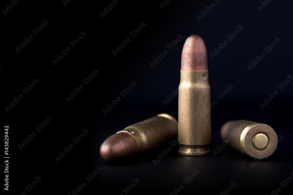 Three pistol bullets on a dark background.