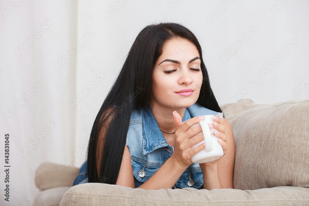 Dark haired woman drinking tea in her living room. Dark haired woman drinking tea in her living room.