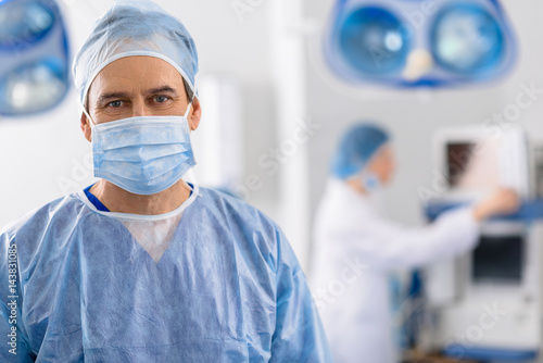 Cheerful male doctor looking carefully