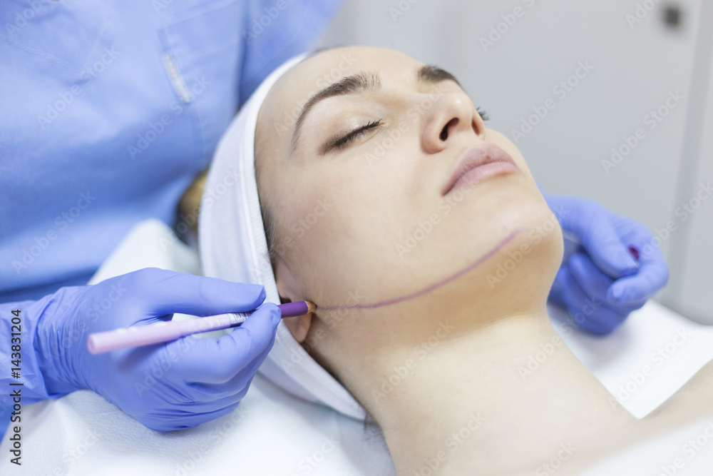 Beautician draw correction lines on woman face. Woman in beauty salon Beautician draw correction lines on woman face. Woman in beauty salon