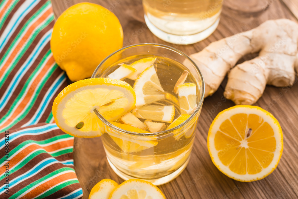 Лимонад с лимоном и имбирем в прозрачном стакане на деревянном столе