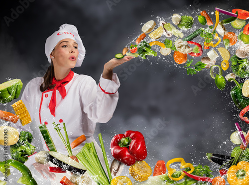 Young woman chef blowing fresh vegetable
