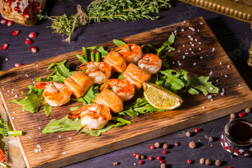 Salmon shish kebab and shrimps, is served with leaves of arugula and a lime