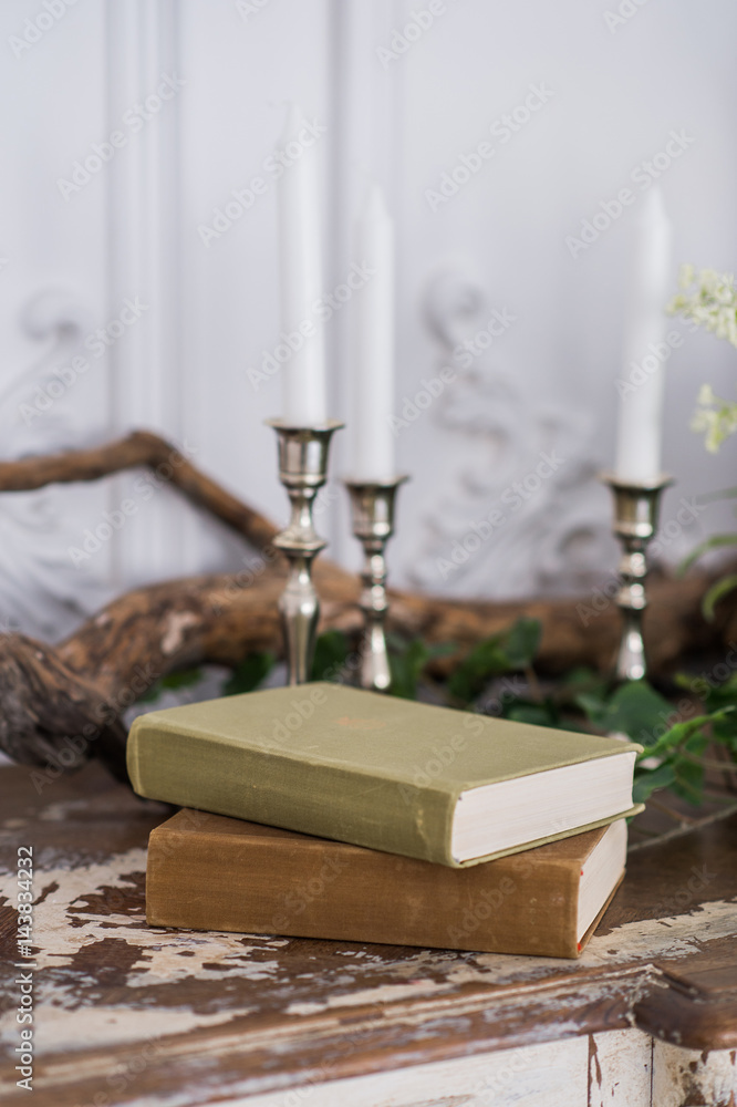 Romantic autumn scenery for photo shoots. Old books, green branch, candles Romantic autumn scenery for photo shoots. Old books, green branch, candles