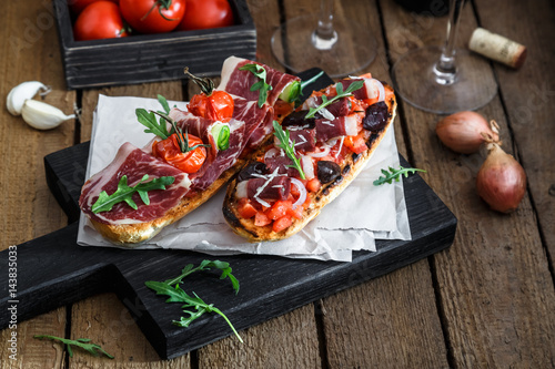 Spanish tapas with slices jamon serrano, salami, olives and cheese cubes on a wooden table. Spanish cuisine