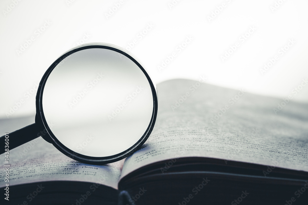 Magnifying glass on open book background. Empty copy space inside