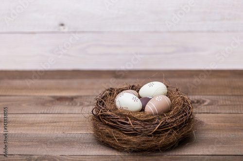 Happy easter! Beautiful Easter eggs are decorated in bed colors in a nest on a wooden background. Easter conceptual background