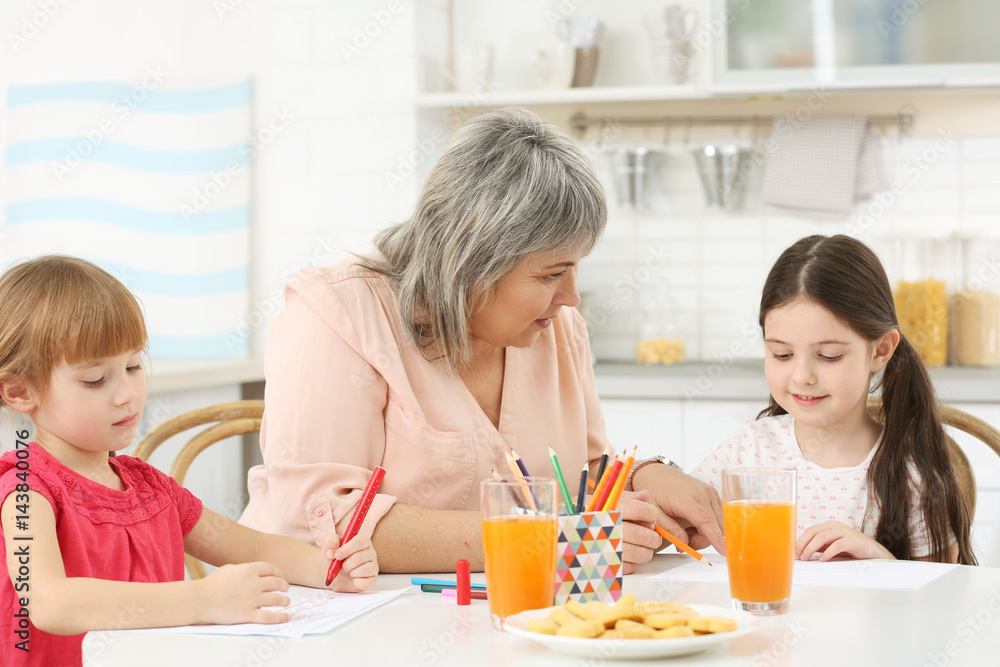 Little girls with grandmother drawing at kitchen table Little girls with grandmother drawing at kitchen table